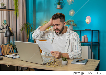 Amazed businessman opening envelope reading bad news in letter feels upset bankruptcy at home office 122093129