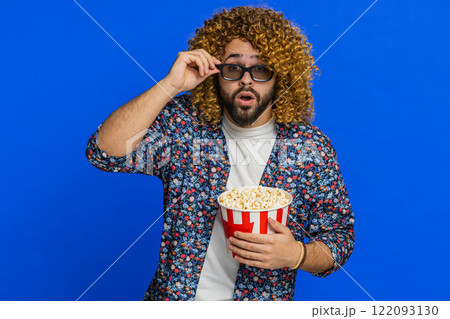 Excited man in 3D glasses eating popcorn watching interesting tv serial sport game cinema film 122093130