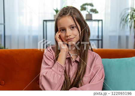 Portrait of happy smiling young girl child kid sitting on home couch 122093196