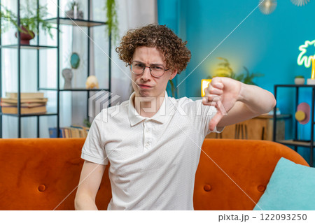 Upset unhappy man showing thumbs down dislike gesture expressing discontent disapproval dissatisfied 122093250