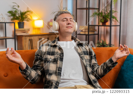 Man listening music, breathes deeply meditating with concentrated thoughts peaceful at home room Man listening music, breathes deeply meditating with concentrated thoughts peaceful at home room 122093315