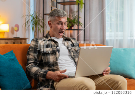 Amazed young man use laptop computer, receive good news message, shocked by victory, celebrate win Amazed young man use laptop computer, receive good news message, shocked by victory, celebrate win 122093316