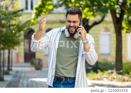 Caucasian young man traveler arguing talking on smartphone while walking on urban city street 122093358
