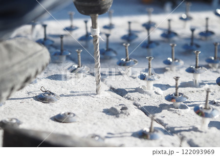 Close-Up of Drilling Process on a Concrete Base with Fasteners Close-Up of Drilling Process on a Concrete Base with Fasteners 122093969