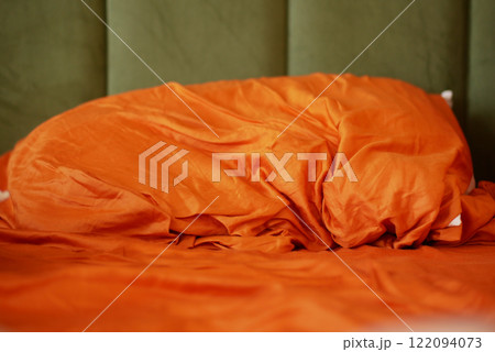 Cozy Orange Bedding with Textured Fabric and Green Background Cozy Orange Bedding with Textured Fabric and Green Background 122094073