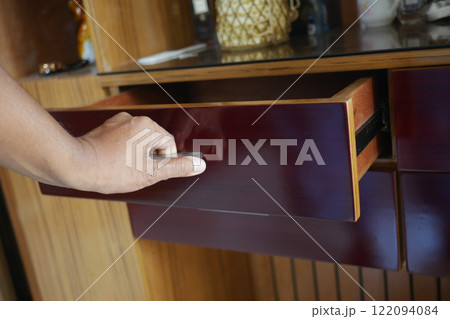 man's hand open drawer wooden in cabinet 122094084