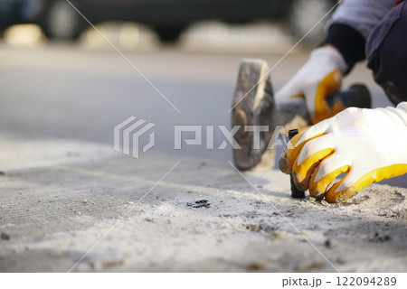 A dedicated worker is repairing the asphalt surface on a city street 122094289