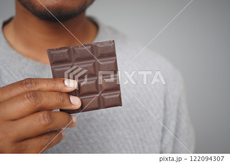 young man eating dark chocolate close up  122094307