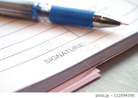 Closeup view of a Blue Pen resting on the Signature Line of Important Documents 122094390