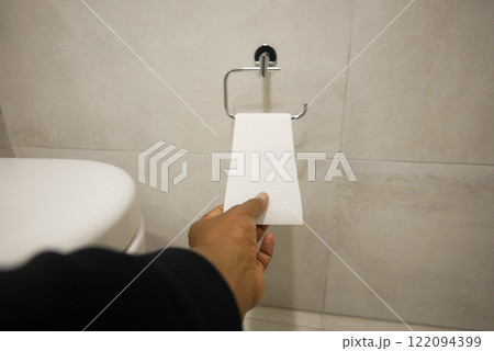 A Hand Reaching for the Toilet Paper Roll in the Bathroom Space A Hand Reaching for the Toilet Paper Roll in the Bathroom Space 122094399