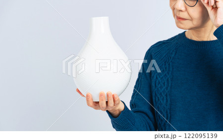 磁器の壺を鑑定するシニア女性 122095139