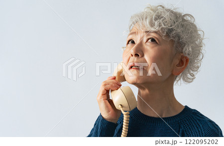 電話しながら落ち込むシニア女性 電話しながら落ち込むシニア女性 122095202