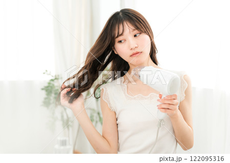 ヘアドライヤーでヘアブロー・髪の毛を乾かす女性（ヘアケア） 122095316