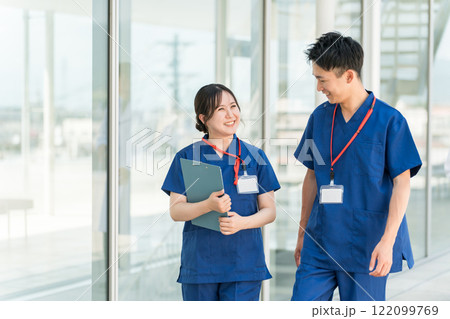病院の通路で話す医者・医師・看護師・医療従事者・ドクター・作業療法士・理学療法士の男女 病院の通路で話す医者・医師・看護師・医療従事者・ドクター・作業療法士・理学療法士の男女 122099769