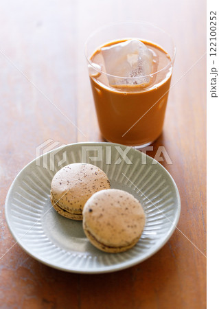 Thai iced tea. Cold drink from Ceylon black tea and milk pouring over ice. Brown orange Ceylon black tea flavor macaron on wooden table. Thai iced tea. Cold drink from Ceylon black tea and milk pouring over ice. Brown orange Ceylon black tea flavor macaron on wooden table. 122100252