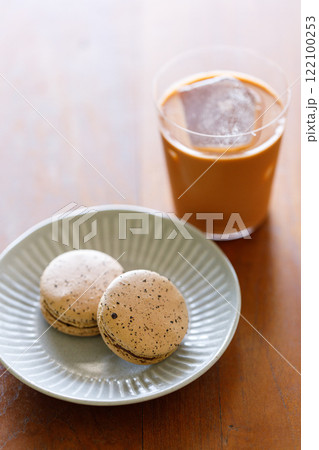 Thai iced tea. Cold drink from Ceylon black tea and milk pouring over ice. Brown orange Ceylon black tea flavor macaron on wooden table. Thai iced tea. Cold drink from Ceylon black tea and milk pouring over ice. Brown orange Ceylon black tea flavor macaron on wooden table. 122100253