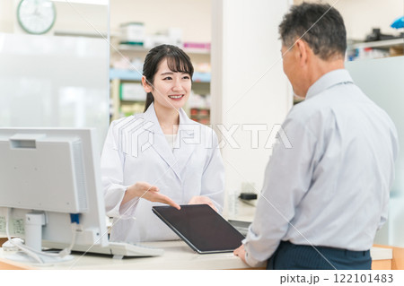 薬局でタブレットPCを使いながら説明する薬剤師・調剤師（レセコン・レセプトコンピュータ） 122101483