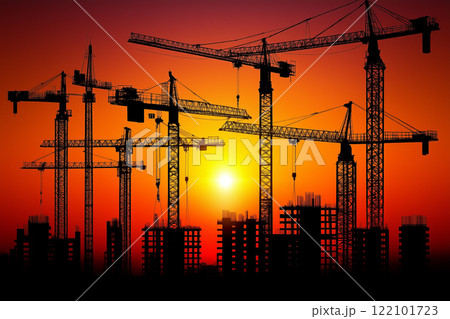 Sunset Over Construction Site with Cranes Silhouetted Against Vibrant Sky Colors 122101723