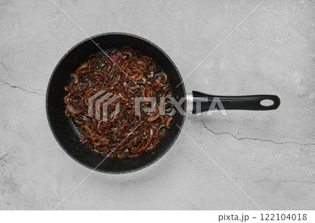 Sauteing caramelized onions in a frying pan on a gray countertop Sauteing caramelized onions in a frying pan on a gray countertop 122104018