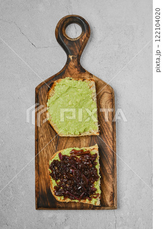Creamy avocado spread and savory onion relish on toasted bread served on a wooden board Creamy avocado spread and savory onion relish on toasted bread served on a wooden board 122104020