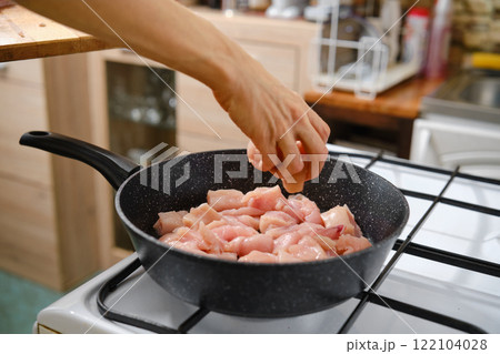Preparing diced chicken for cooking in a kitchen setting during daylight hours Preparing diced chicken for cooking in a kitchen setting during daylight hours 122104028