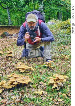 Photographer taking pictures of mushrooms in the forest Photographer taking pictures of mushrooms in the forest 122104776