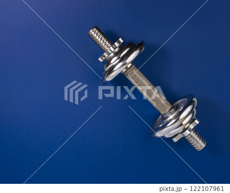 Stainless metal dumbbell on dark blue background with copyspace for text 122107961