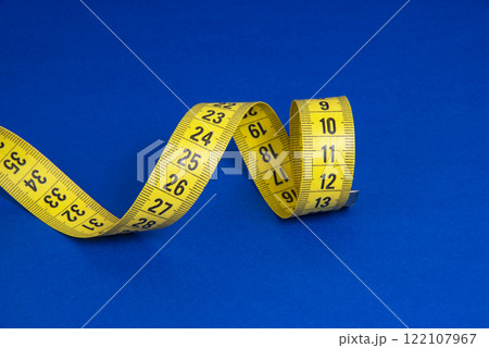 Yellow spiral tape measure on dark blue background 122107967