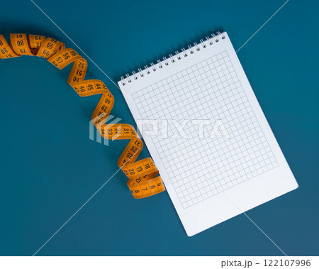 Colorful spiral tape measure and notebook on bright background 122107996