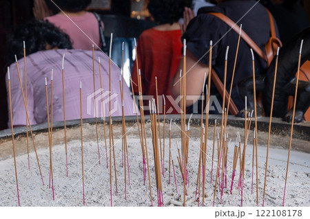 Burning incense candles in a pot in the temple, with blurred background of people praying 122108178