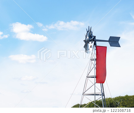 Windmill weather vane with red flag on blue sky background Windmill weather vane with red flag on blue sky background 122108718