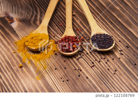 Dry different spices in spoons on wooden background Dry different spices in spoons on wooden background 122108769