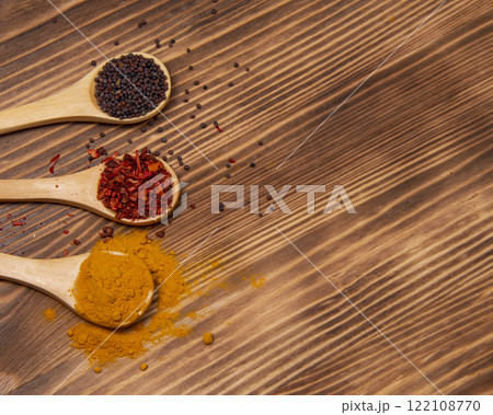 Dry different spices in spoons on wooden background Dry different spices in spoons on wooden background 122108770