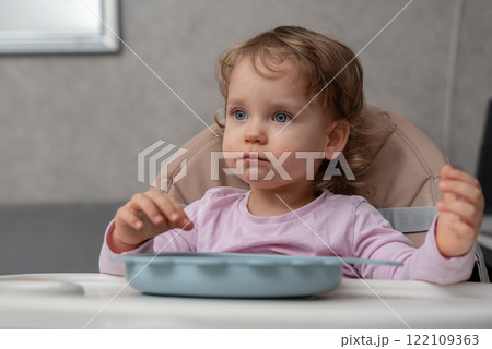 A thoughtful toddler sitting at the table during a quiet moment at home 122109363