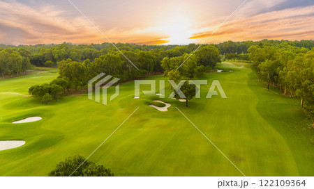 A breathtaking sunset view of a golf course with lush greenery and tranquil surroundings. 122109364