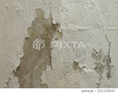 cement surface with a fragment of fallen plaster, part of an old dilapidated building macro background of old cracked texture of gray-white shade, a piece of concrete wall with fallen off whitewash 122110043