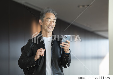 スマートフォンの画面を見るバックパックを持った60代の男性 122111829