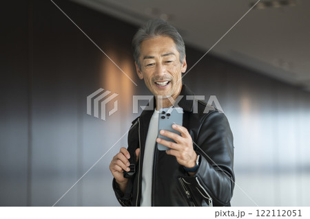 スマートフォンの画面を見る笑顔の60代の男性 スマートフォンの画面を見る笑顔の60代の男性 122112051
