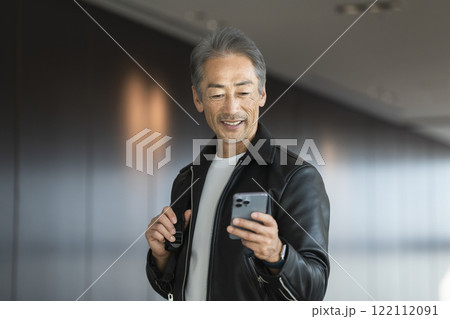 スマートフォンの画面を見る笑顔のシニア男性 122112091