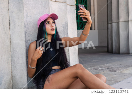 A young woman recording a story for social media on a staircase landing A young woman recording a story for social media on a staircase landing 122113741