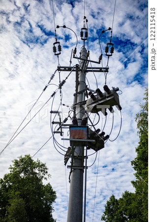 A large electricity power line stretches across the blue sky adorned with fluffy clouds 122115418