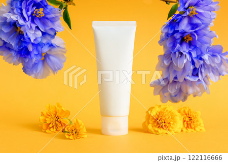 cosmetic moisturizer cream tube, blue flowers and marigolds on yellow background. skincare, body cream, gel, sunblock, sunscreen, shampoo, sun skin protection. blank bottle template mockup 122116666