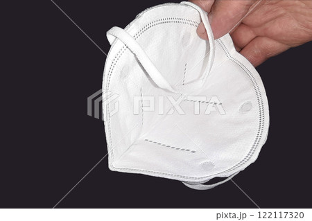 Protective face mask, respirator back white in a man hand. Heart on a dark background Protective face mask, respirator back white in a man hand. Heart on a dark background 122117320