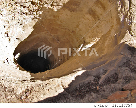 Dried up water well in desert. Yellow texture of sandstone and rope ladder. Round hole in ground. 122117754