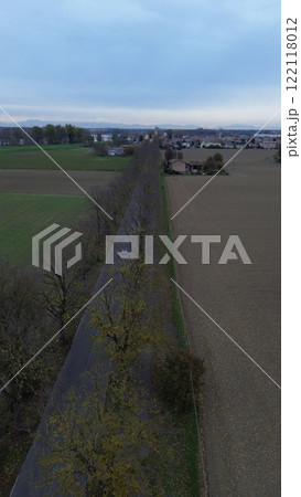 Vertical aerial view of san nazzaro, monticelli d'ongina, italy, showing road, trees, fields, and houses in autumn 122118012