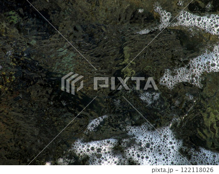 Textured sea foam with bubbles in a shallow spot above the rocky bottom Textured sea foam with bubbles in a shallow spot above the rocky bottom 122118026