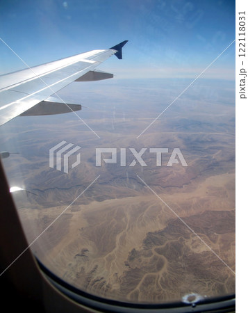 View From the Plane Porthole Overlooking Desert Mountains and Valleys During Daylight 122118031