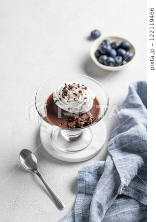 Chocolate pudding in a glass with whipped cream on a light background Chocolate pudding in a glass with whipped cream on a light background 122119466