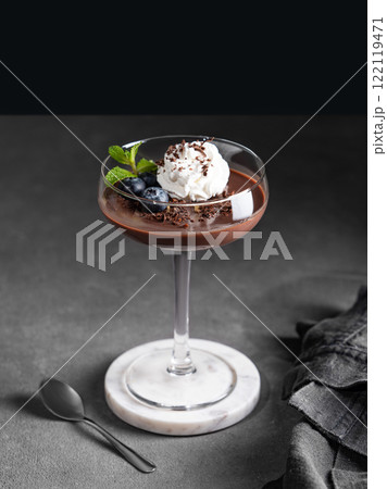 Chocolate pudding in a glass with whipped cream, fresh blueberries and mint on a dark background Chocolate pudding in a glass with whipped cream, fresh blueberries and mint on a dark background 122119471