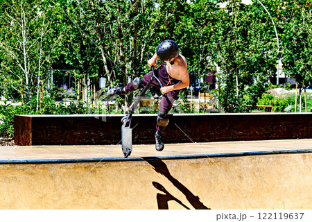 Young man practicing Scootering (Freestyle Scootering) in the new SkatePark of the central park of Igualada, Barcelona, Spain Young man practicing Scootering (Freestyle Scootering) in the new SkatePark of the central park of Igualada, Barcelona, Spain 122119637